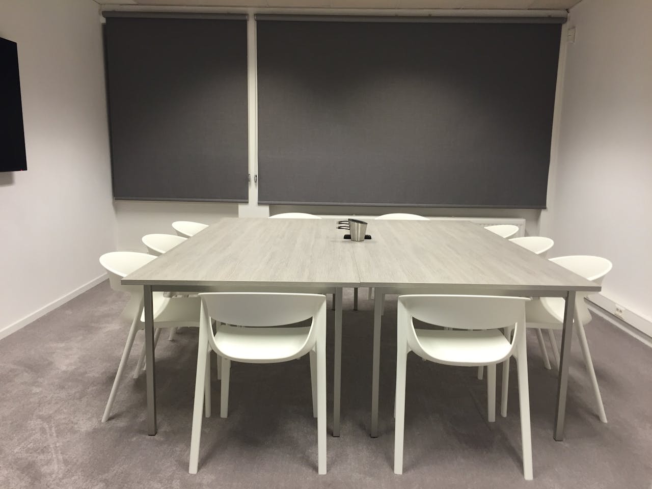 heros-img Contemporary minimalist meeting room with modern furniture and gray blinds.